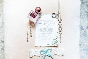 Wedding invitation with floral design elements and blue ribbon on white surface.
