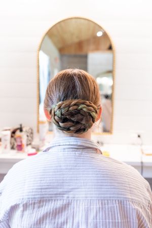 Elegant braided updo hairstyle viewed from behind in a gold-framed mirror.