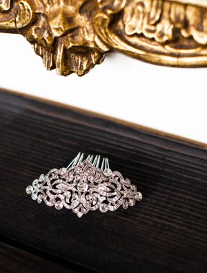 Close-up of an ornate crystal and silver hair comb against a dark wooden surface.