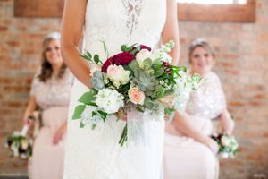 Close-up of a bridal bouquet with burgundy and white flowers, greenery and succulents.