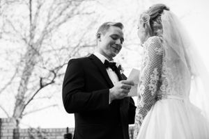 A black and white moment of a couple exchanging vows during their outdoor winter wedding ceremony.