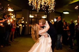 Romantic first dance moment under twinkling lights at an indoor wedding reception.