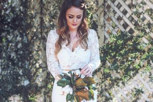 Romantic bridal portrait with lace wedding dress against garden trellis background.