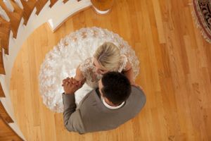 Overhead view of couple dancing on hardwood floor with bride's dress creating circular pattern.