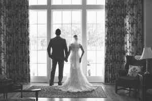 Silhouette of couple standing by large window in formal attire.