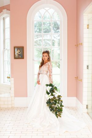 Bridal portrait in pink room with arched window and flowing white gown.