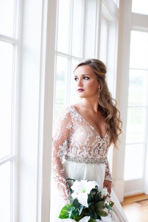 Bridal portrait with detailed lace sleeve gown and white floral bouquet.