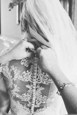 Close-up detail of intricate lace and buttons on the back of a wedding dress.
