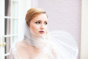 A close up bridal portrait showcasing delicate lace details and flowing white veil against a bright window backdrop.