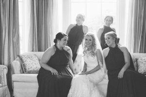 Black and white photo of bridal party relaxing on couch during wedding preparations.