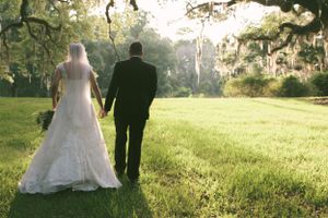 Romantic wedding couple walking through a moss-draped Southern garden at sunset.