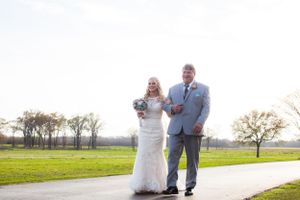 Couple walking along path in sunlit outdoor setting during wedding.