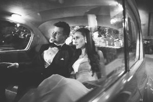 Black and white portrait of newlyweds inside classic car.