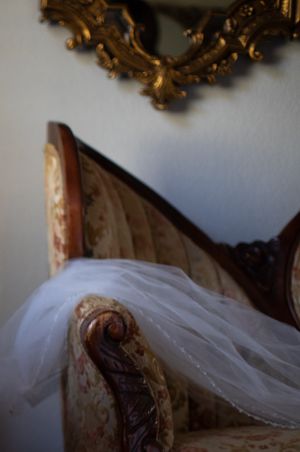 White wedding veil draped over vintage gilded furniture with ornate details.