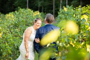 Newlyweds share a joyful moment among sunlit yellow flowers in a garden setting.