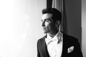 Dramatic black and white portrait of formal attire against window light.