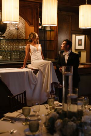 An elegant scene in a wood-paneled bar area with pendant lights and formal table settings.