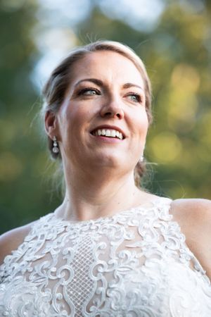 A close-up portrait showing joyful expression and lace wedding dress details.
