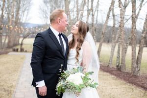 Wedding couple sharing intimate moment among birch trees in winter landscape.