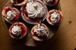 Red velvet cupcakes topped with swirled white frosting arranged on a wooden serving platter.