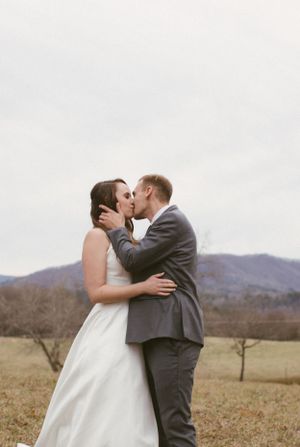 A tender moment captured between a couple in wedding attire against a mountain backdrop.