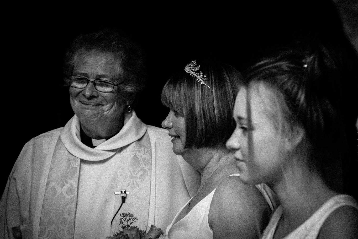Black and white photograph of female vicar, bride and bridesmaid at wedding in Yorkshire