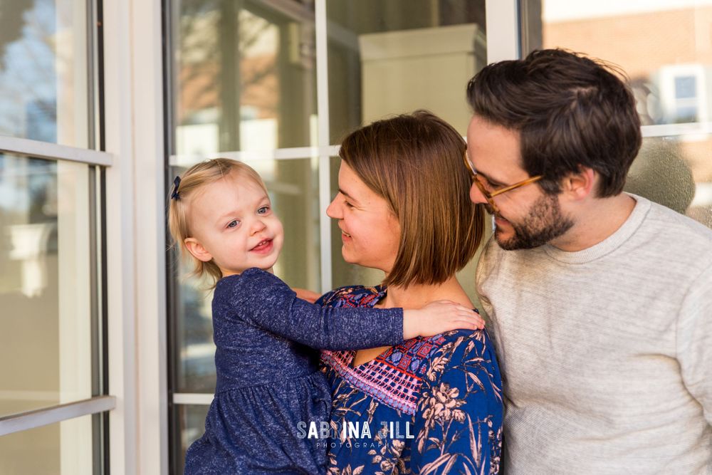 Little girl with her parents in front of window