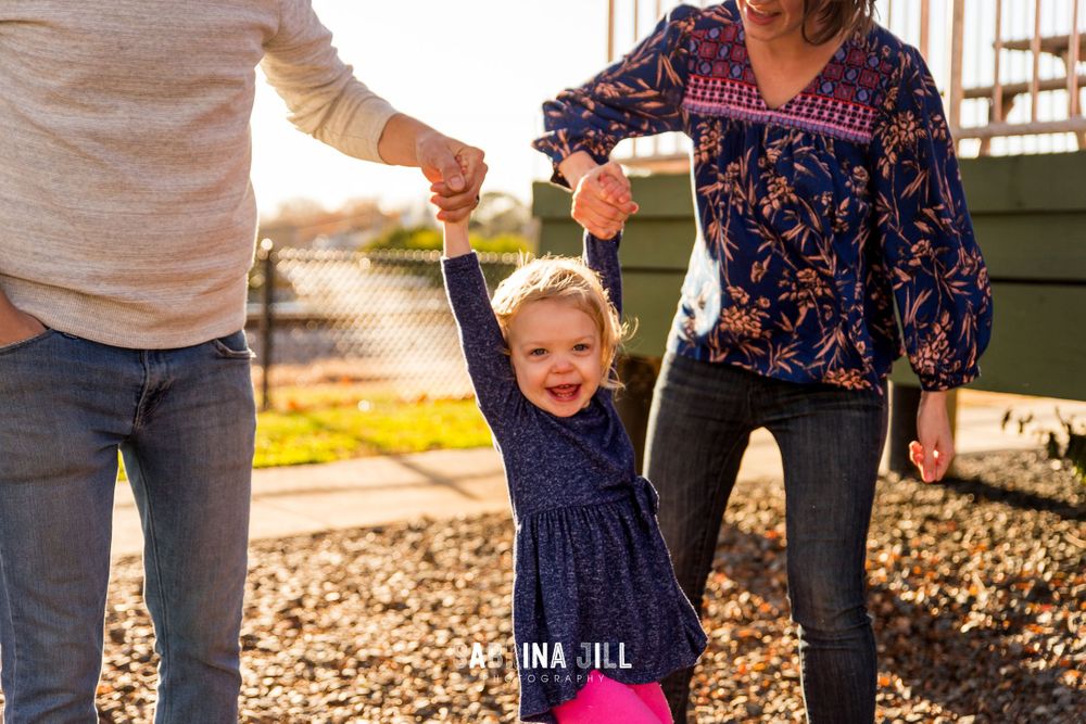 Little girl getting swung by her parents