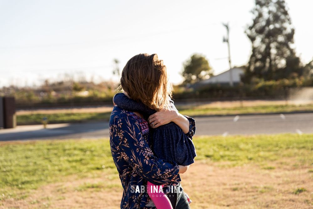 Mom and daughter hugging in the sunset