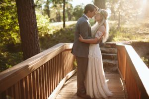 A romantic sunset moment on a wooden bridge surrounded by pine trees.
