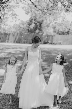 A joyful moment captured in black and white with flowing white dresses in a garden setting.