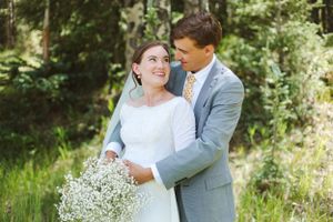 Romantic outdoor wedding portrait with baby's breath bouquet against natural greenery.