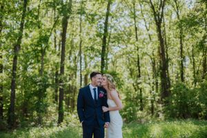 Newlyweds sharing intimate moment in sunlit forest setting.