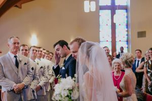 A traditional church wedding ceremony with attendants in grey suits and white floral bouquets.