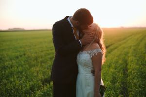 A tender moment between newlyweds in a golden sunset field.