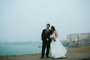 Coastal wedding portrait with moody sky and waterfront backdrop.