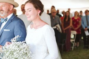 Wedding ceremony under a tent with delicate baby's breath bouquet and joyful expressions.