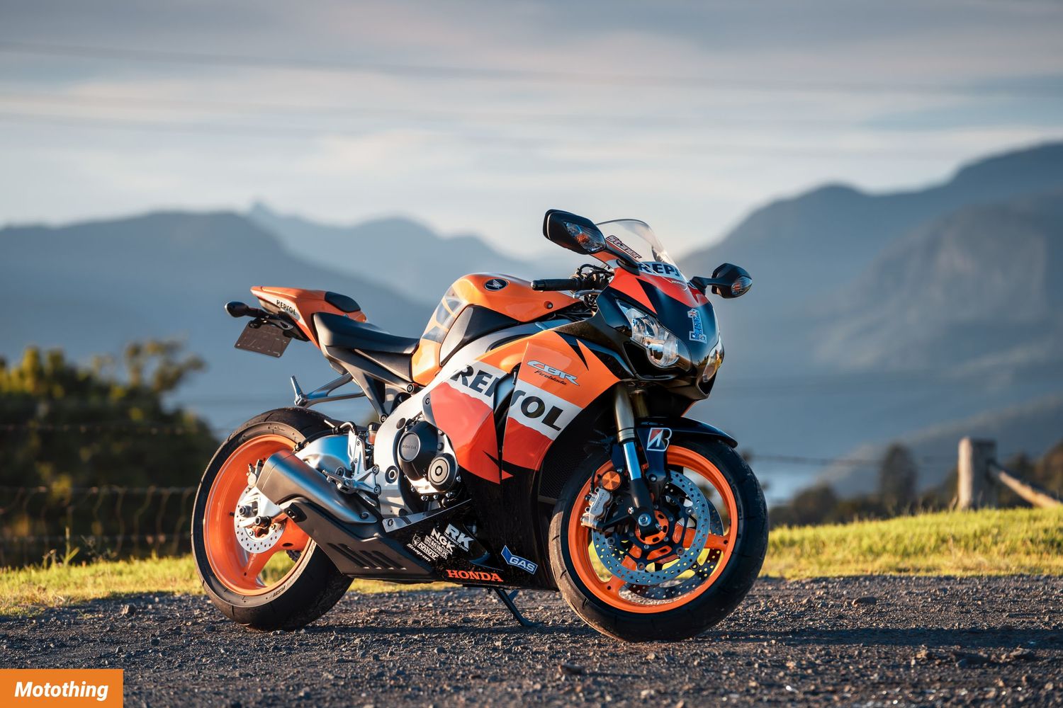 Orange and black KTM sportbike parked on hilltop with mountain landscape backdrop.