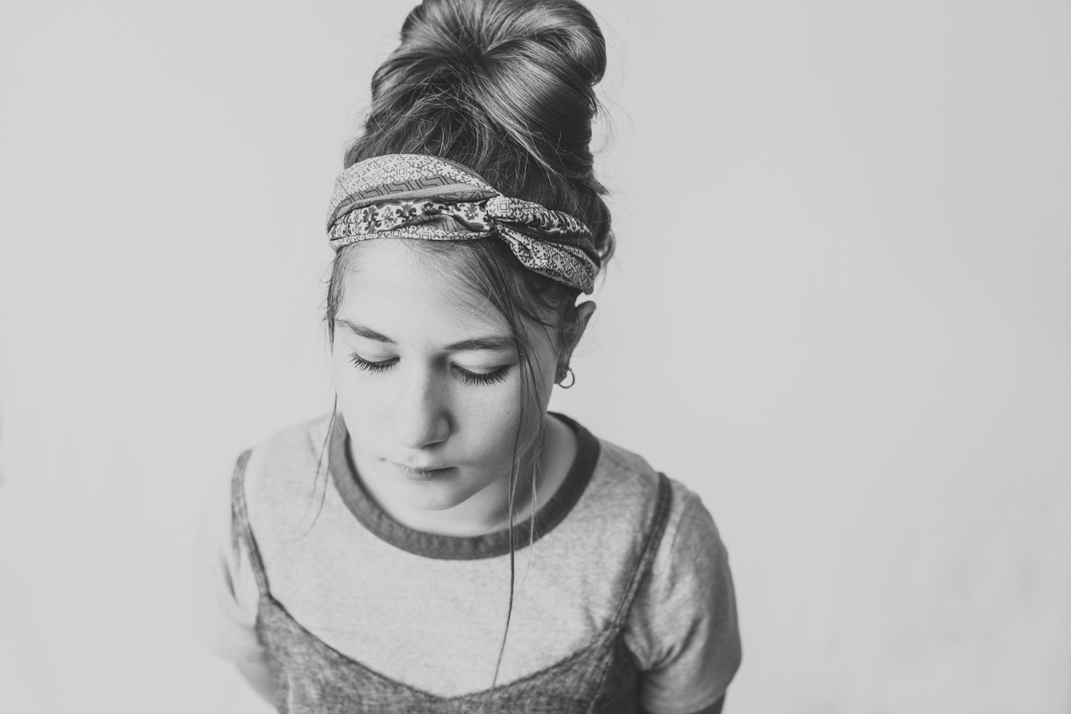 Black and white close-up portrait with patterned headband and downward gaze.