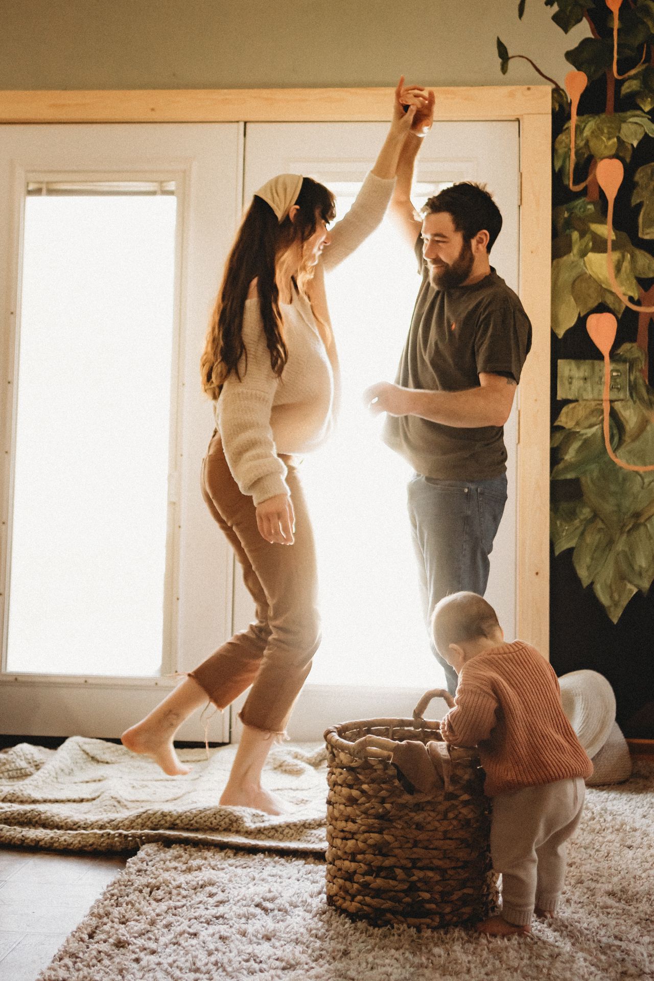 A playful domestic scene with dancing and movement in a sunlit room with woven basket.