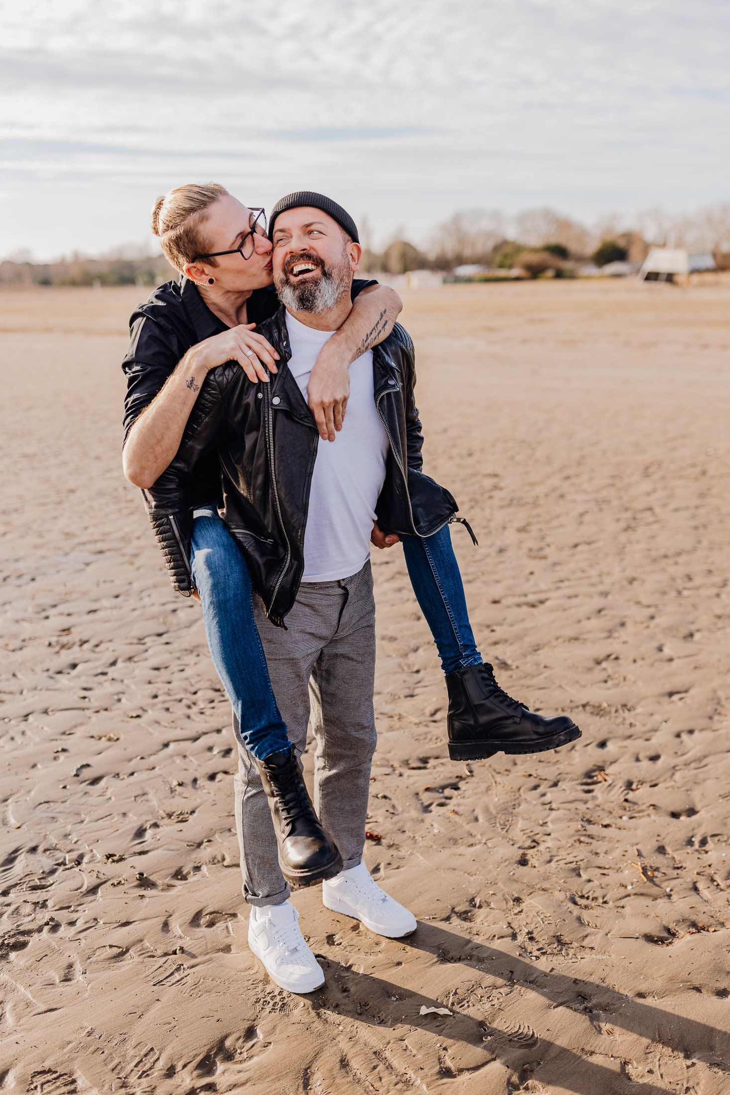 Verspieltes Paar hat Spaß am Sandstrand während des Sonnenuntergangs-Fotoshootings.