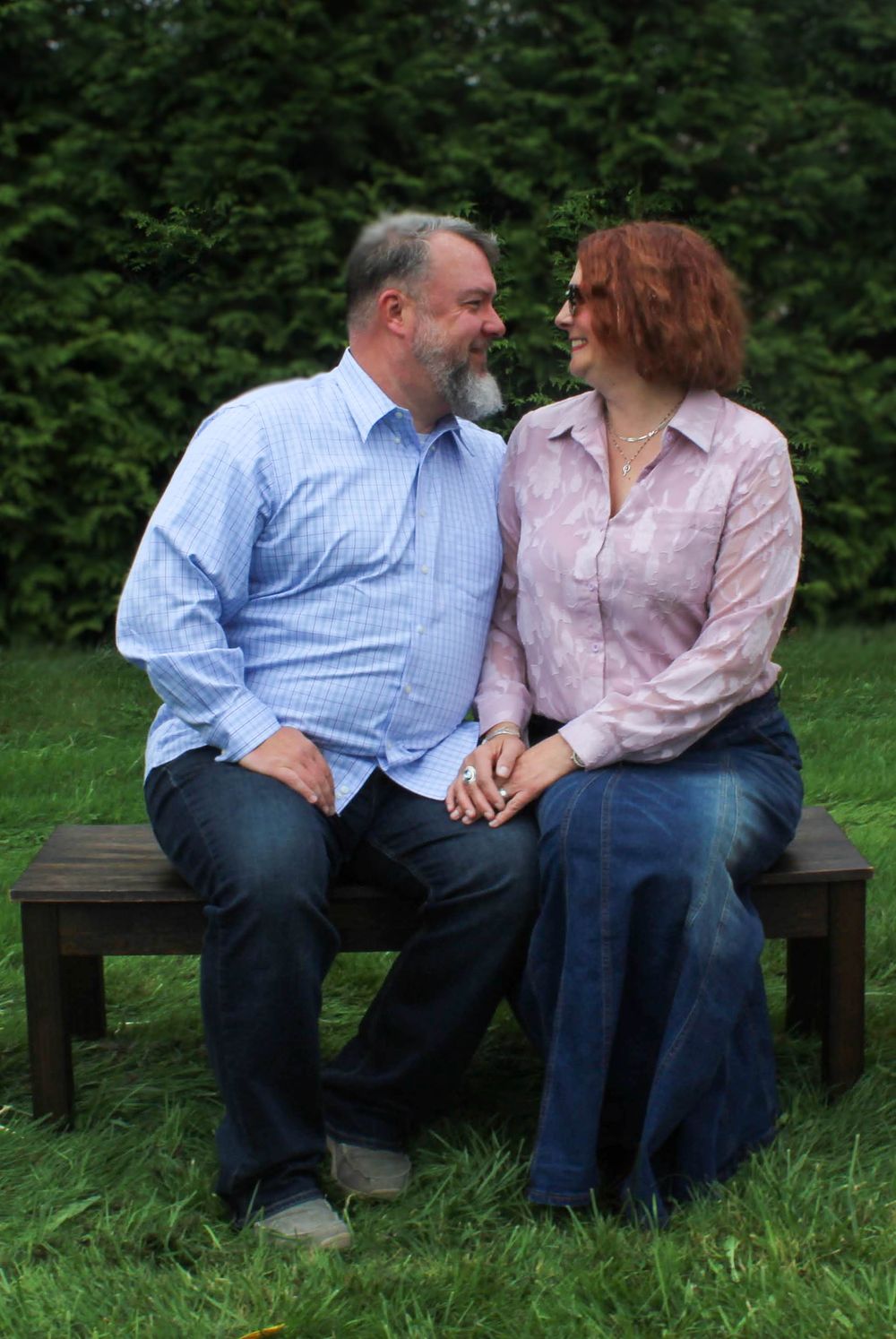 Couple sharing intimate moment while sitting together on wooden bench outdoors.