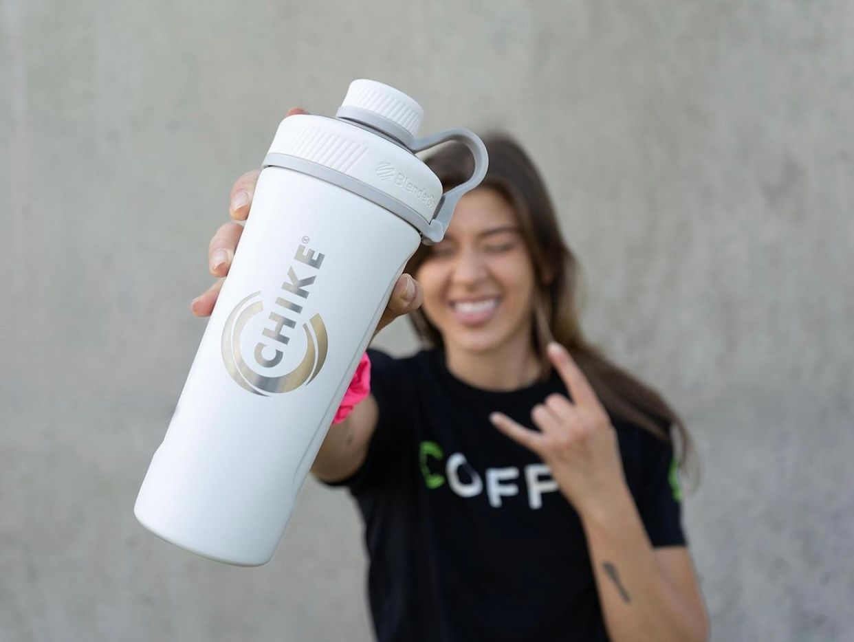 Client posing with white coffee mug against neutral background.