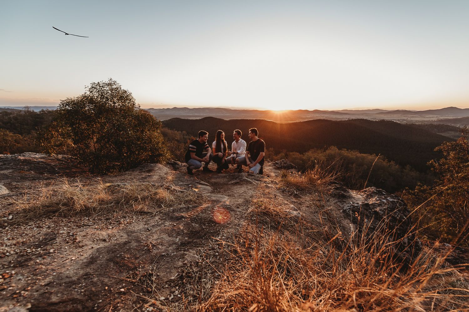 A group enjoys sunset views from a rocky mountaintop overlook.
