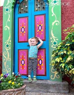 Colorful doorway with whimsical painted designs and bright turquoise trim against pink wall.