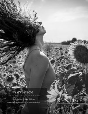 An artistic black and white portrait of a woman with flowing hair in a sunflower field.