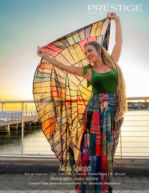 Model in green top twirls colorful patterned skirt against sunset backdrop by water.