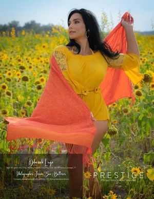 Woman in yellow dress stands gracefully in vibrant sunflower field with flowing orange scarf.