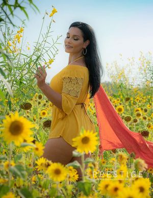 Artistic maternity photoshoot amidst blooming sunflower field in warm sunlight.