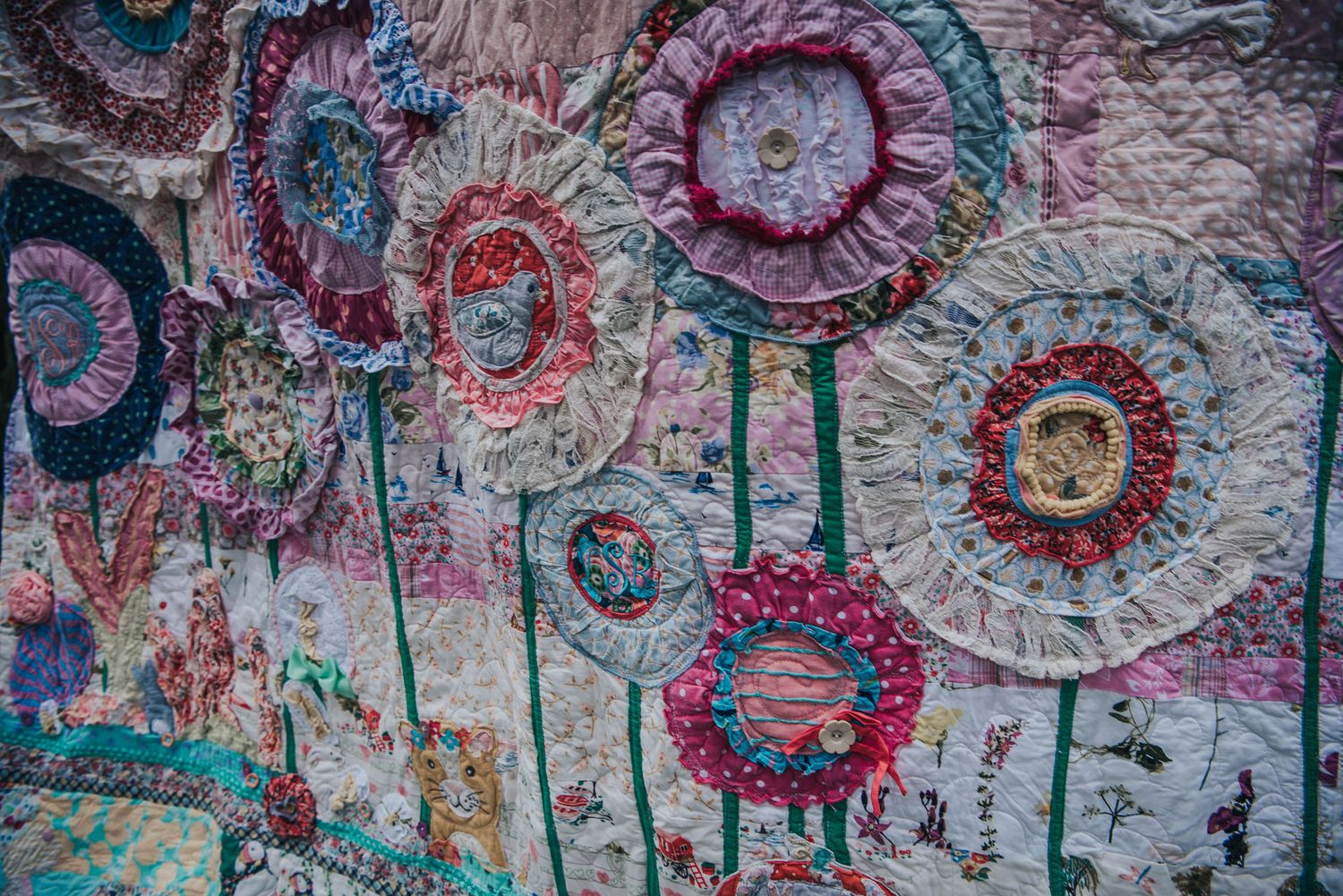 Highly textured memory quilt with lots of flowers made from baby clothes.